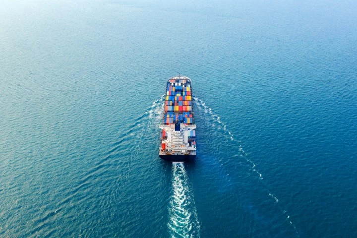 Freighter ship at sea, moving away from the viewer.